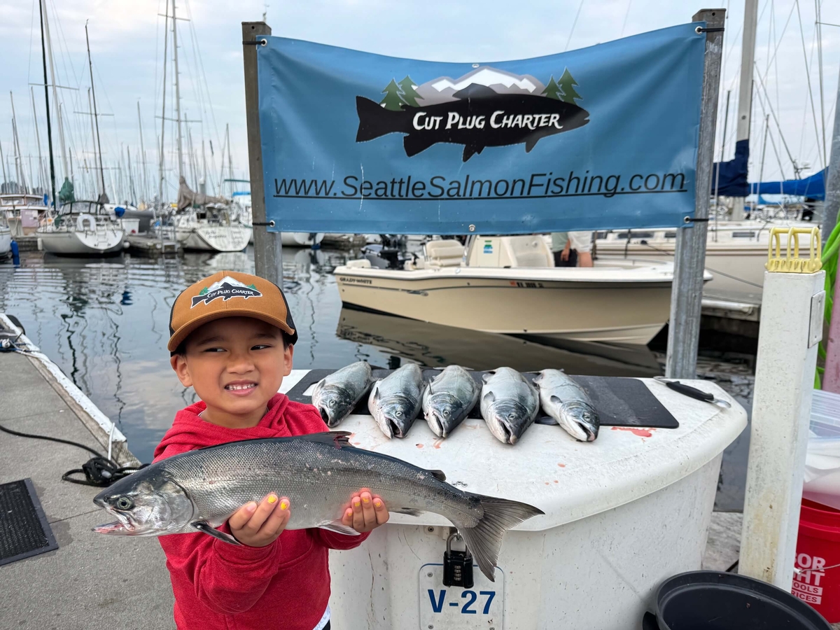 Child smiling and holding a salmon at the Shilshole Bay Marina in Seattle